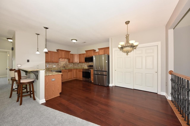 kitchen featuring appliances with stainless steel finishes, a peninsula, a chandelier, pendant lighting, and backsplash