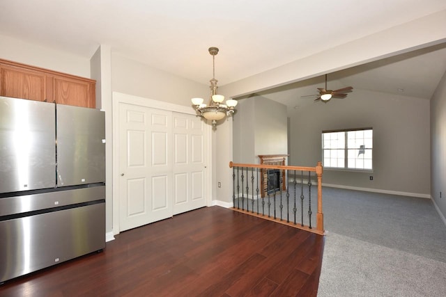 unfurnished dining area with ceiling fan, a chandelier, dark wood finished floors, baseboards, and lofted ceiling