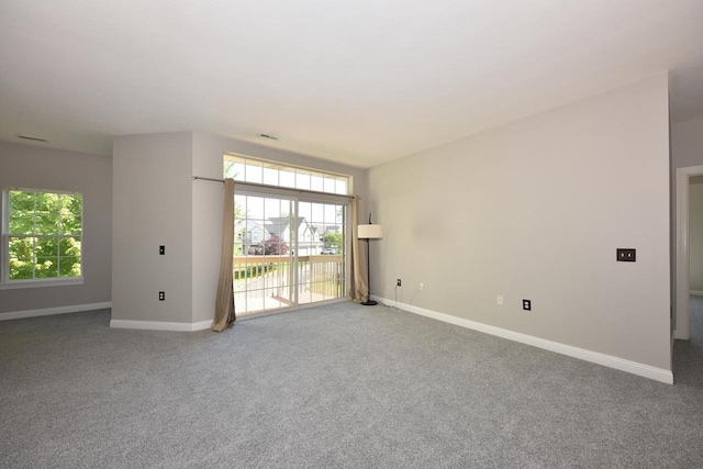 carpeted empty room featuring baseboards and plenty of natural light
