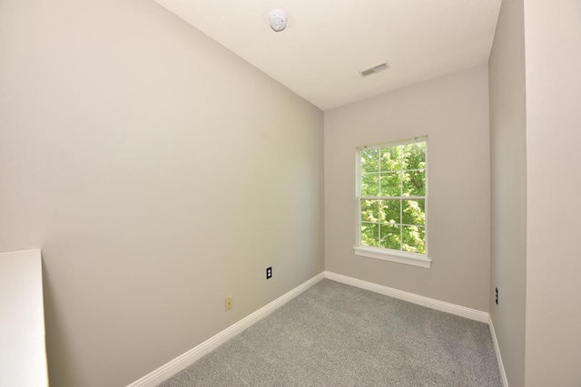empty room featuring baseboards, light carpet, and a smoke detector