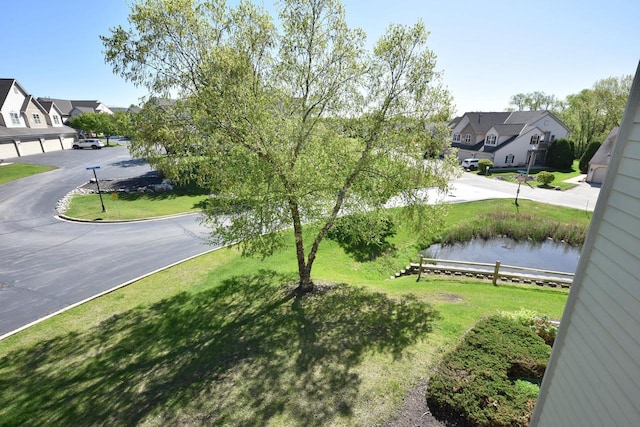 view of yard featuring a water view, fence, and a residential view