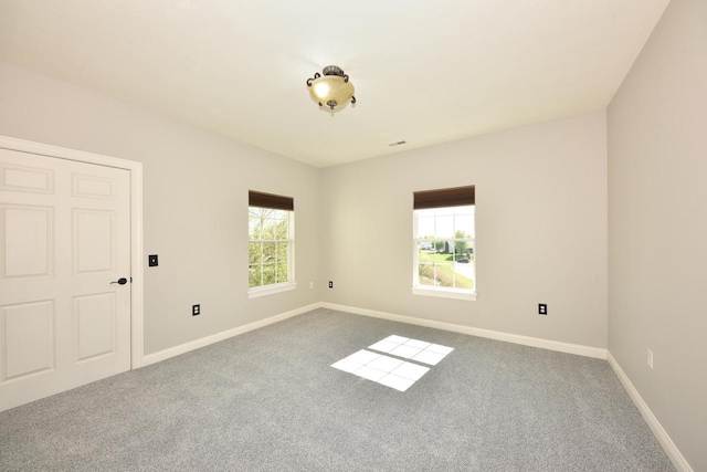 carpeted spare room featuring baseboards