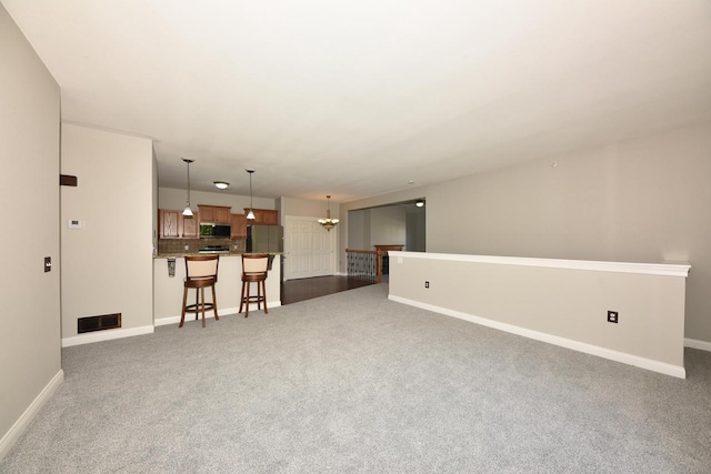 unfurnished living room with carpet floors, a chandelier, and baseboards
