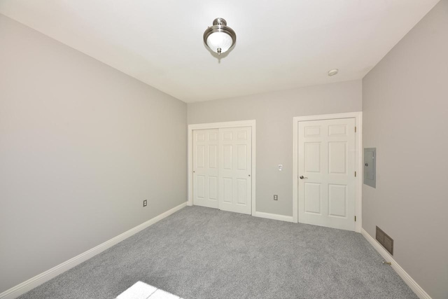 unfurnished bedroom featuring carpet floors, baseboards, a closet, and electric panel