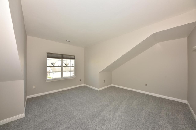bonus room featuring dark colored carpet and baseboards