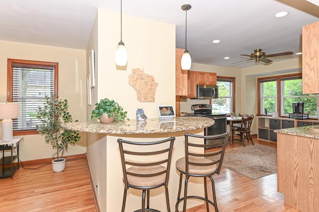 2377 S 73rd St, West Allis, WI 53219 - kitchen with appliances with stainless steel finishes, light wood-style floors, a kitchen breakfast bar, light stone counters, and recessed lighting