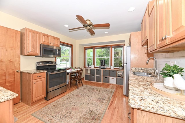 2377 S 73rd St, West Allis, WI 53219 - kitchen featuring appliances with stainless steel finishes, a sink, light wood finished floors, light stone counters, and a ceiling fan