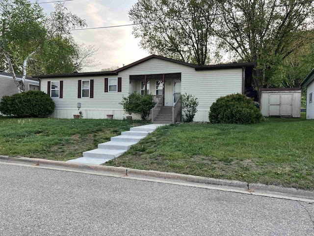 view of front of home featuring a front yard, an outdoor structure, and a shed