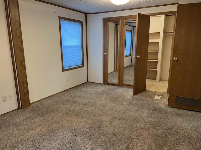 unfurnished bedroom featuring carpet floors, a textured ceiling, and multiple windows