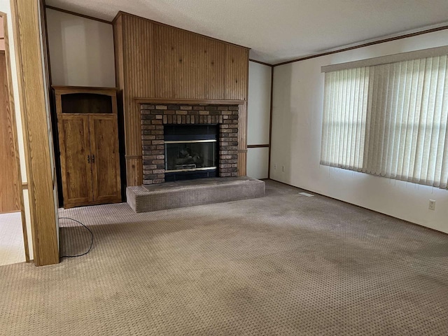 unfurnished living room featuring carpet floors, crown molding, a brick fireplace, and a textured ceiling