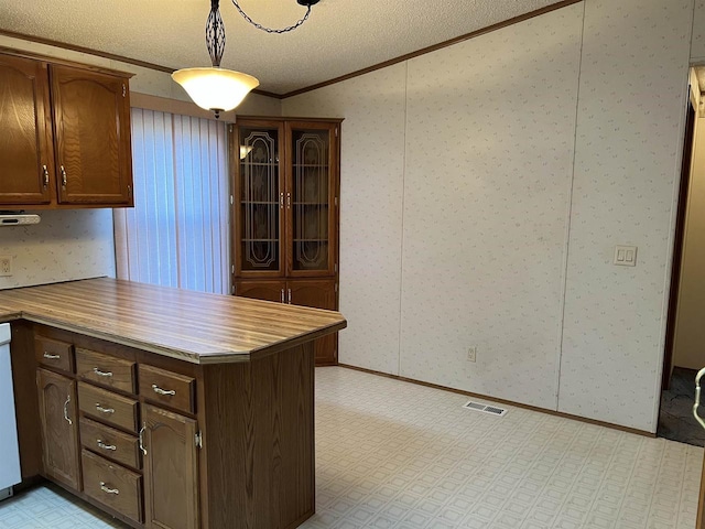 kitchen featuring ornamental molding, light floors, a peninsula, wallpapered walls, and a textured ceiling