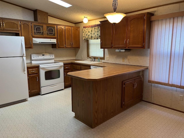 kitchen with white appliances, range hood, light floors, vaulted ceiling, and a sink