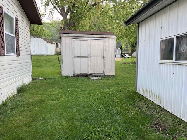 view of grassy yard with a storage shed and an outbuilding