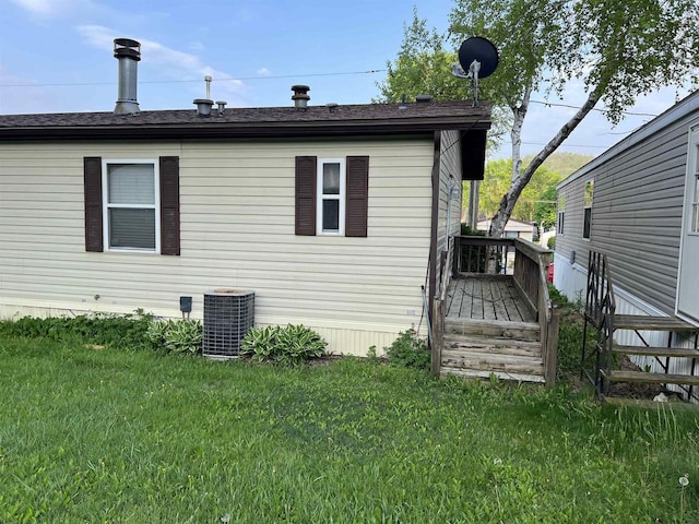 view of side of property with central AC unit, a yard, and a wooden deck