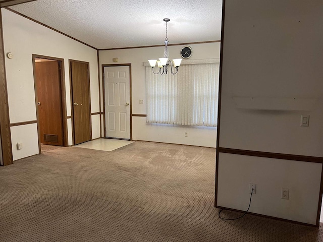 unfurnished dining area featuring carpet flooring, a chandelier, ornamental molding, and a textured ceiling