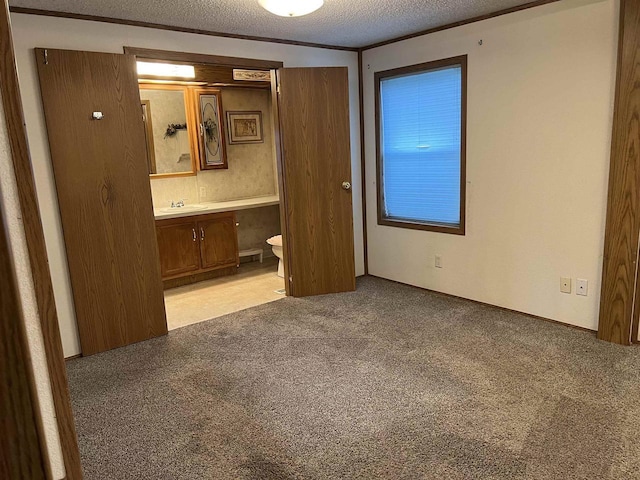 unfurnished bedroom with a textured ceiling, connected bathroom, light carpet, and a sink