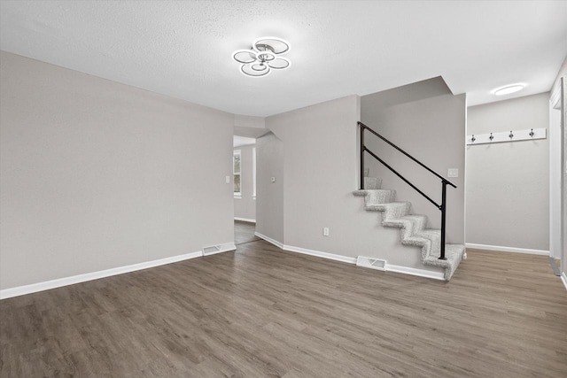 1143 S 23rd St, Manitowoc, WI 54220 - unfurnished living room featuring wood finished floors, baseboards, stairway, and a textured ceiling