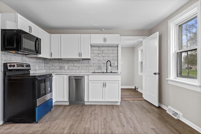 1143 S 23rd St, Manitowoc, WI 54220 - kitchen featuring electric range oven, a sink, stainless steel dishwasher, black microwave, and light countertops