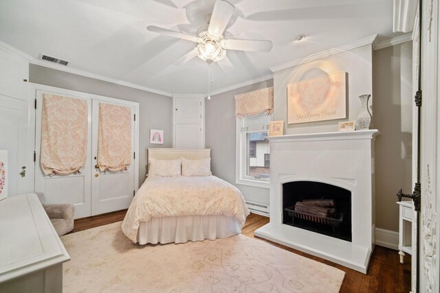 2663 N Wahl Ave, Milwaukee, WI 53211 - bedroom featuring a baseboard heating unit, wood finished floors, ornamental molding, ceiling fan, and a fireplace with raised hearth