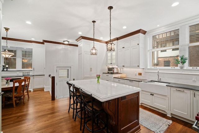 2663 N Wahl Ave, Milwaukee, WI 53211 - kitchen featuring a sink, crown molding, a breakfast bar area, dark wood finished floors, and decorative light fixtures
