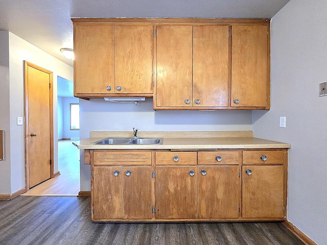 kitchen with a sink, dark wood-type flooring, baseboards, and brown cabinetry