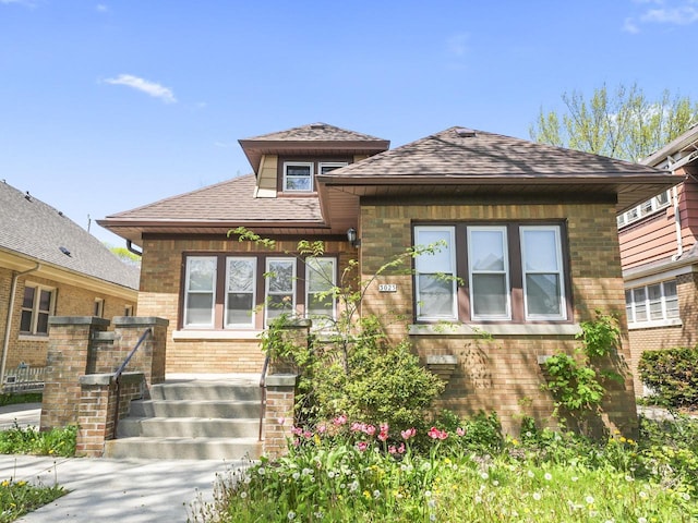 view of front of house with a shingled roof and brick siding