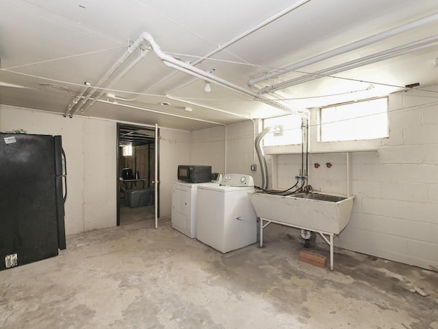 basement featuring freestanding refrigerator, washing machine and dryer, and a sink