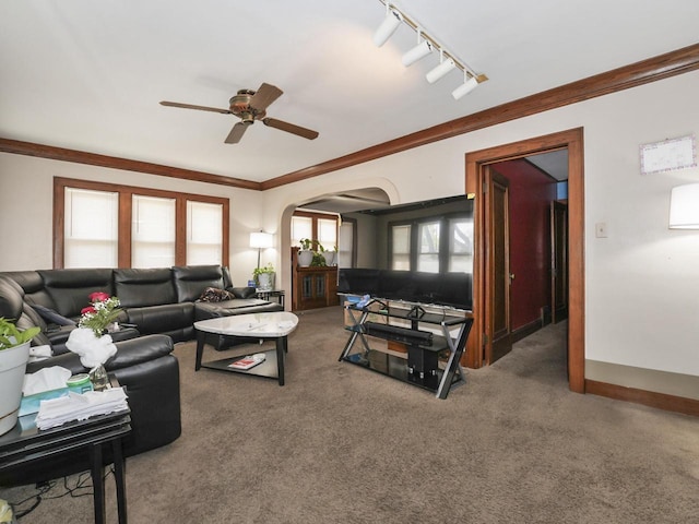 carpeted living room with arched walkways, a ceiling fan, ornamental molding, and track lighting