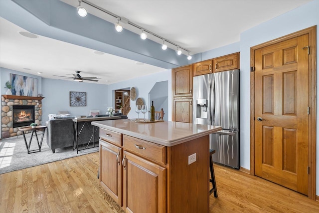 4024 Oakmont Trl, Waukesha, WI 53188 - kitchen with stainless steel fridge with ice dispenser, a center island, light wood finished floors, and ceiling fan