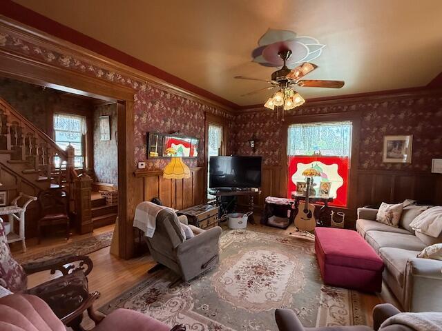 400 S Water St, Sparta, WI 54656 - living area featuring healthy amount of natural light, wallpapered walls, wainscoting, a ceiling fan, and stairway