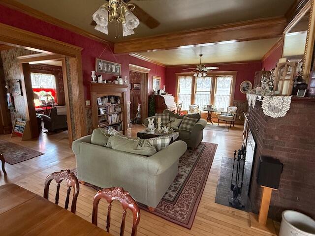 400 S Water St, Sparta, WI 54656 - living room featuring a ceiling fan, a fireplace, light wood finished floors, ornamental molding, and beamed ceiling