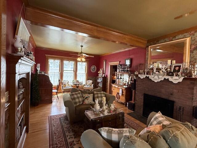 400 S Water St, Sparta, WI 54656 - living room featuring a fireplace, ornamental molding, wood finished floors, ceiling fan, and beamed ceiling