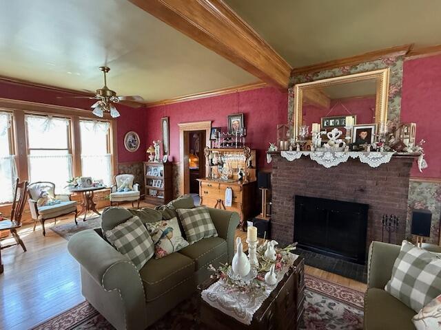 400 S Water St, Sparta, WI 54656 - living room featuring wood finished floors, crown molding, a ceiling fan, a brick fireplace, and beam ceiling