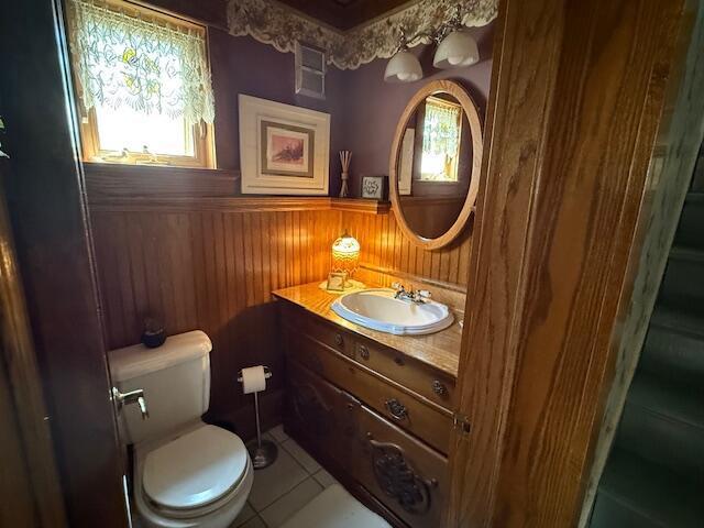 400 S Water St, Sparta, WI 54656 - bathroom featuring a wainscoted wall, wooden walls, tile patterned flooring, toilet, and vanity