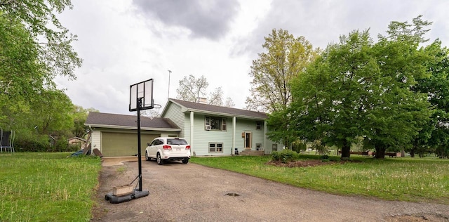105 Glenview Dr, Tomah, WI 54660 - raised ranch featuring asphalt driveway, a front lawn, an attached garage, a chimney, and a trampoline