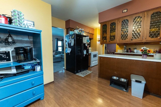 105 Glenview Dr, Tomah, WI 54660 - kitchen featuring black refrigerator with ice dispenser, white range with electric cooktop, light wood finished floors, light countertops, and brown cabinetry