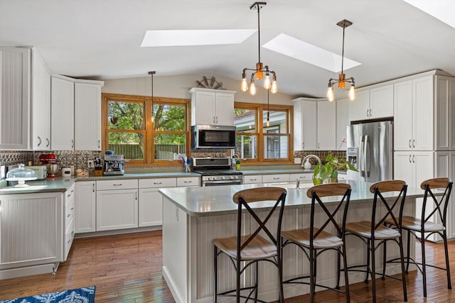 4531 Tabor Rd, Racine, WI 53402 - kitchen featuring stainless steel appliances, a skylight, vaulted ceiling, tasteful backsplash, and white cabinets