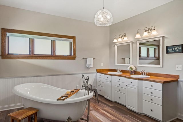 4531 Tabor Rd, Racine, WI 53402 - bathroom with wood finished floors, wainscoting, a soaking tub, double vanity, and a chandelier