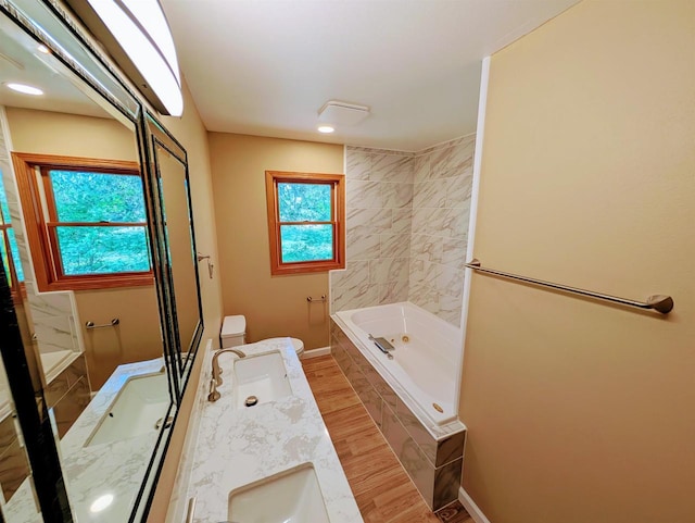 73 Church St, Montello, WI 53949 - full bathroom featuring tiled bath, wood finished floors, double vanity, recessed lighting, and baseboards