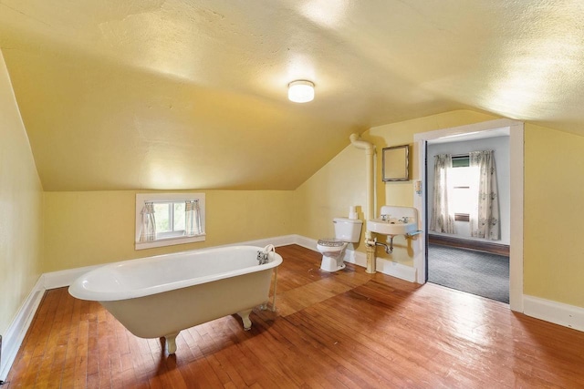 407 E Franklin St, Portage, WI 53901 - full bathroom featuring hardwood / wood-style floors, a soaking tub, a textured ceiling, baseboards, and lofted ceiling