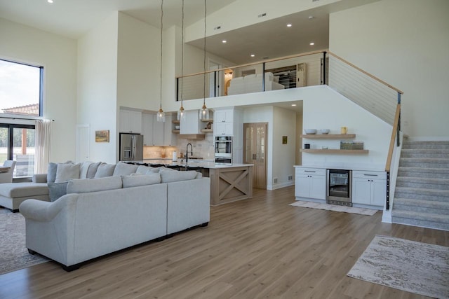 W5613 37th St, New Lisbon, WI 53950 - living area with a high ceiling, beverage cooler, stairs, light wood-style floors, and recessed lighting