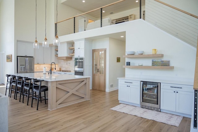 W5613 37th St, New Lisbon, WI 53950 - kitchen with open shelves, beverage cooler, appliances with stainless steel finishes, high vaulted ceiling, and light wood-type flooring