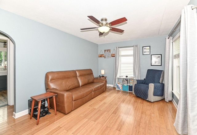 134 W Roberta Ave, Waukesha, WI 53186 - living room with arched walkways, baseboards, ceiling fan, light wood-style flooring, and plenty of natural light