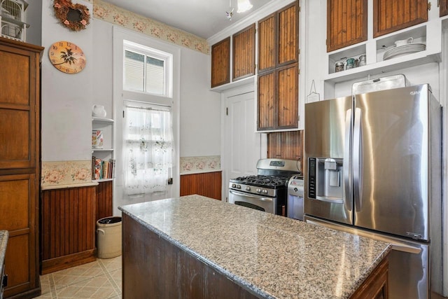 503 E Conant St, Portage, WI 53901 - kitchen featuring stainless steel appliances, open shelves, wainscoting, a kitchen island, and brown cabinets