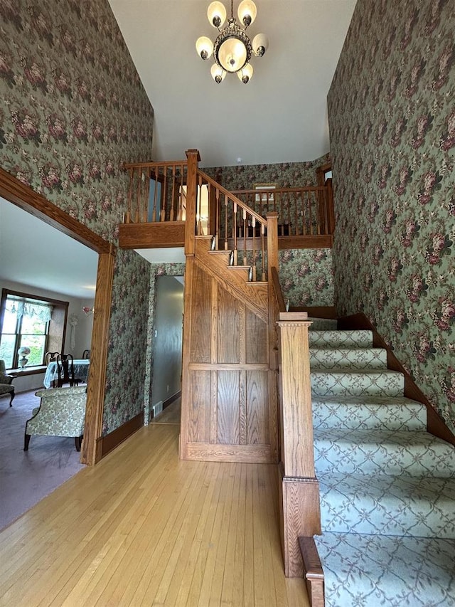 13412 Glacier Rd, Tomah, WI 54660 - stairway featuring wallpapered walls, a chandelier, hardwood / wood-style floors, and baseboards