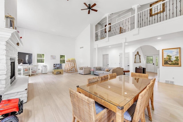 W6870 Czech Ln, Neshkoro, WI 54960 - dining room with high vaulted ceiling, a ceiling fan, a fireplace, arched walkways, and light wood-style floors