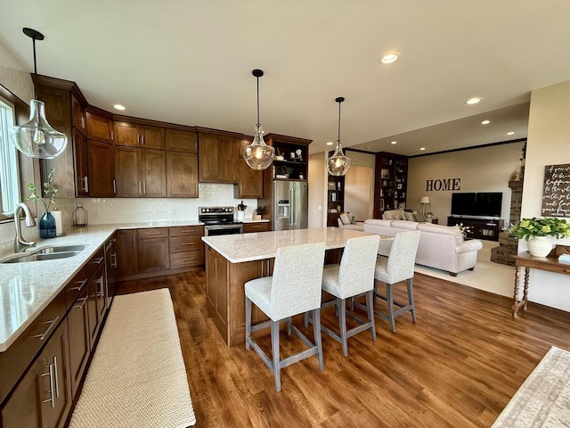 515 Fieldstone Ct, Tomah, WI 54660 - kitchen featuring a sink, appliances with stainless steel finishes, dark wood finished floors, a kitchen island, and decorative backsplash