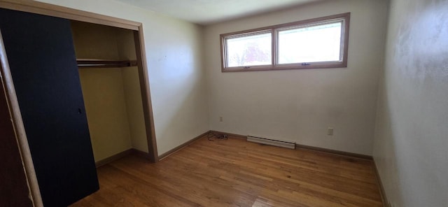 2905 S 18th St, Sheboygan, WI 53081 - unfurnished bedroom featuring a closet, wood finished floors, baseboards, and a baseboard heating unit