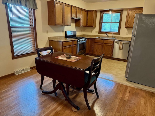 W9519 Skogen Rd, Cambridge, WI 53523 - kitchen with appliances with stainless steel finishes, brown cabinetry, a sink, and light wood finished floors