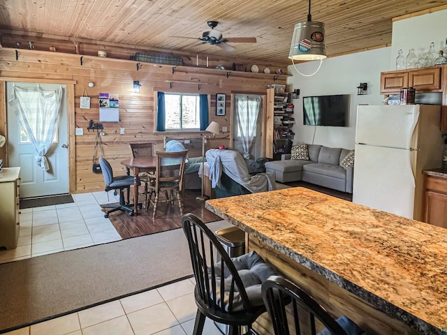 2284 Spirit Ln, La Pointe, WI 54850 - dining space with light tile patterned flooring, light colored carpet, a ceiling fan, wood ceiling, and wood walls